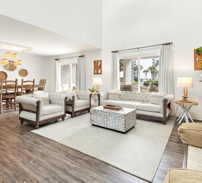 Relax in your bright, open living space featuring cozy tufted seating and natural textures that create the perfect atmosphere for unwinding.