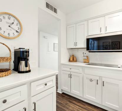 Your pristine white kitchen awaits with modern appliances and charming touches—perfect for brewing morning coffee or preparing meals.