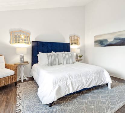 Your coastal-inspired bedroom features crisp linens, nautical pendant lights, and a cozy wicker reading chair perfect for unwinding.