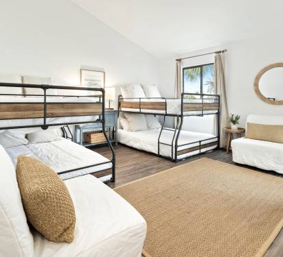 Your spacious bedroom features multiple bunk beds with crisp white linens and natural textures, perfect for families or groups.