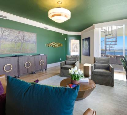 Sink into plush seating in your stylish living space, where emerald walls and ocean views create the perfect backdrop for relaxation.
