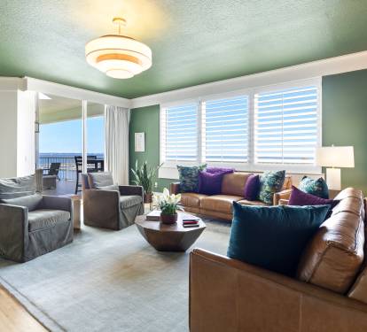 Sink into plush leather seating while ocean views fill your windows in this stylish living space with vibrant art and warm lighting.
