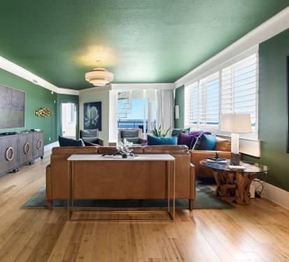 Relax in your stylish living room with rich emerald walls and warm hardwood floors, where vibrant artwork creates perfect ambiance.