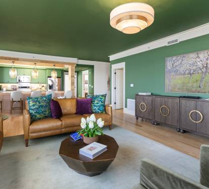 Relax in your stylish living room with vibrant emerald walls, leather seating, and modern art creating a sophisticated retreat.