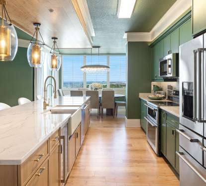 Cook in your gourmet kitchen featuring stunning ocean views, stainless steel appliances, and elegant pendant lighting creating the perfect culinary retreat.