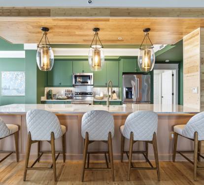 Gather around this stunning kitchen island with stylish bar seating, where warm wood meets refreshing green tones for memorable meal prep together.