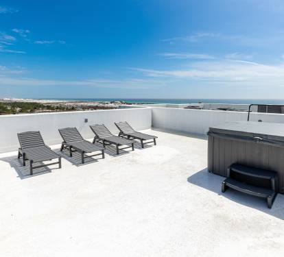 Your private rooftop paradise features loungers and a hot tub with stunning coastal views for ultimate relaxation.