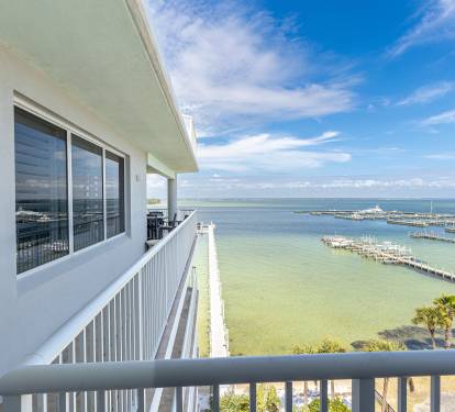 Stunning waterfront balcony overlooking pristine marina and turquoise bay waters under endless blue skies.