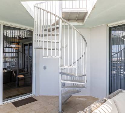 Stunning spiral staircase connects your multi-level retreat, with floor-to-ceiling windows framing panoramic views from your private terrace.