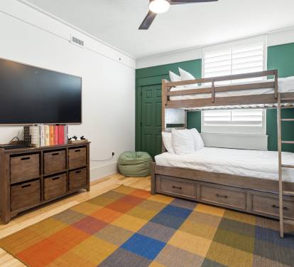 Your kids will love this cheerful bunk bed room with its vibrant colorful rug and entertainment setup for cozy family nights in.