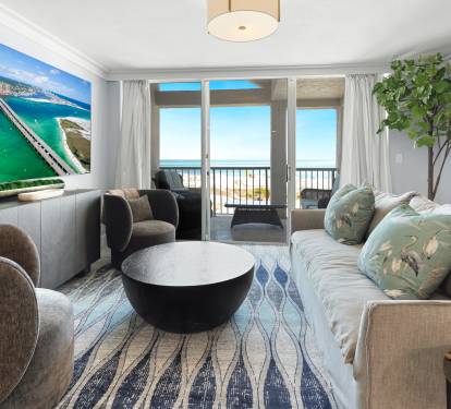 Unwind in this stylish living room where coastal artwork meets ocean views through your private balcony doors.