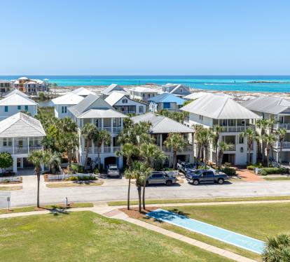 Elevated coastal community featuring modern beach homes with stunning turquoise waters and pristine white sand beaches stretching into the horizon.