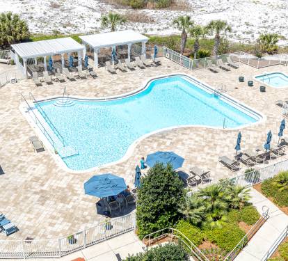 Aerial view of the resort's pool complex featuring a uniquely-shaped swimming pool surrounded by comfortable loungers and beach amenities.