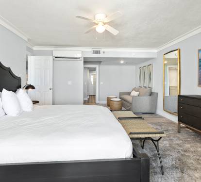 Sink into crisp white linens and unwind in your stylish bedroom sanctuary, complete with a cozy seating area and ocean artwork.