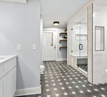 Indulge in this spacious master bathroom featuring a luxurious soaking tub, glass-enclosed shower, and elegant star-patterned floors for your relaxing retreat.