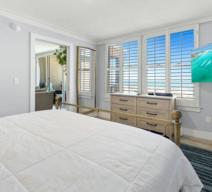 Your peaceful bedroom features a comfortable bed, built-in dresser, and shuttered windows that frame stunning ocean views.