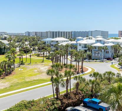 Elevated view showcasing a coastal resort community with palm-lined streets and modern beach houses near the shoreline.