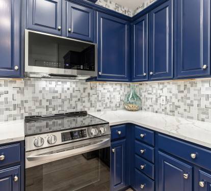 Your stylish kitchen features rich navy cabinets, gleaming marble counters, and modern appliances ready for your culinary adventures.