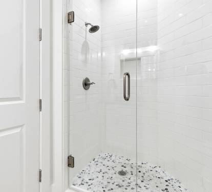 Step into your pristine glass-enclosed shower featuring elegant subway tiles and a beautiful mosaic floor that adds charm to your daily routine.