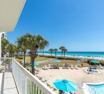 Beachfront property overlooking pristine white sand beach and emerald Gulf waters with palm-lined pool deck and direct beach access.