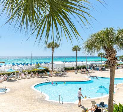 Resort pool deck with crystal-clear waters and direct beach access overlooking pristine white sand and turquoise ocean.
