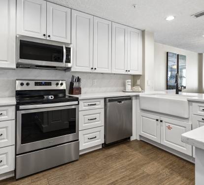 Your modern kitchen features crisp white cabinetry, stainless appliances, and spacious countertops perfect for preparing meals during your stay.