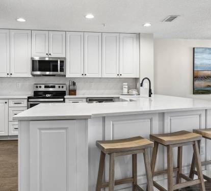 Your spacious kitchen features crisp white cabinetry, gleaming countertops, and modern appliances, perfect for preparing memorable meals during your stay.