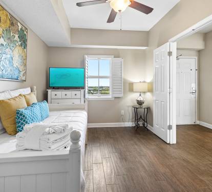 Your cozy coastal bedroom features comfortable bedding, entertainment system, and peaceful window views for ultimate relaxation.