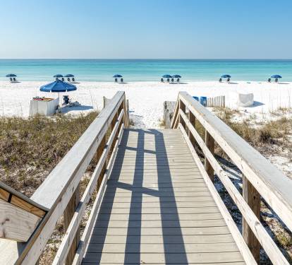 Pristine white sand beach with turquoise waters and convenient boardwalk access just steps from the property.