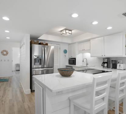Your bright, modern kitchen awaits with sleek white cabinetry, stainless steel appliances, and a spacious island perfect for morning coffee or evening meals.