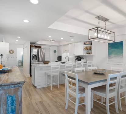 Your open-concept kitchen flows seamlessly into the dining area, where ocean-inspired artwork sets a calming coastal mood.
