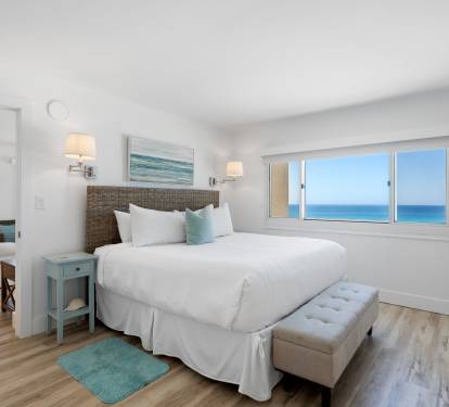 Wake up to stunning ocean views through your bedroom window, where crisp white linens and coastal decor create the perfect seaside retreat.
