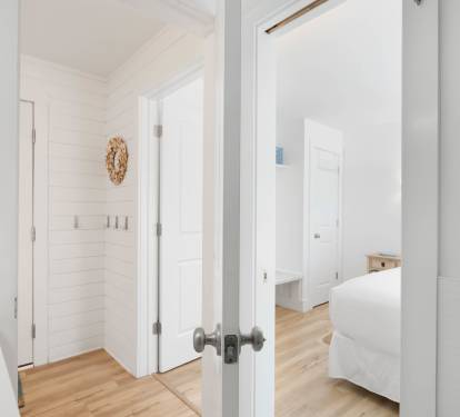 Step into your bright, airy retreat where crisp white walls and warm hardwood floors create a serene sanctuary for your coastal getaway.