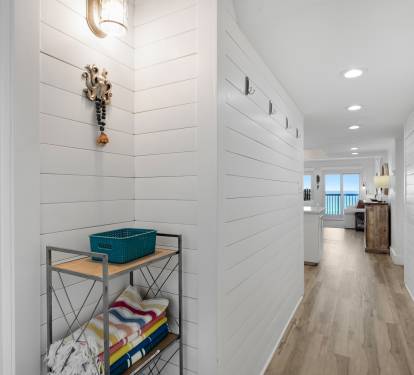 Walk through your bright hallway past the organized bathroom and into your coastal living space with gulf views beyond.