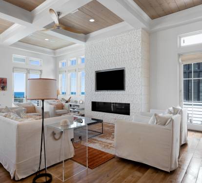 Unwind in your elegant living space with soaring coffered ceilings, cozy fireplace, and stunning ocean views through floor-to-ceiling windows.