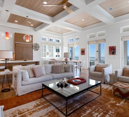 Relax in this stunning open-concept space where warm wood meets coastal elegance, with soaring coffered ceilings and breathtaking ocean views.