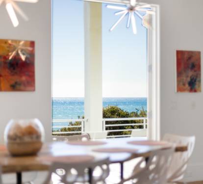 Your dining space opens to breathtaking ocean views through floor-to-ceiling windows, where modern art meets coastal serenity for unforgettable meals.