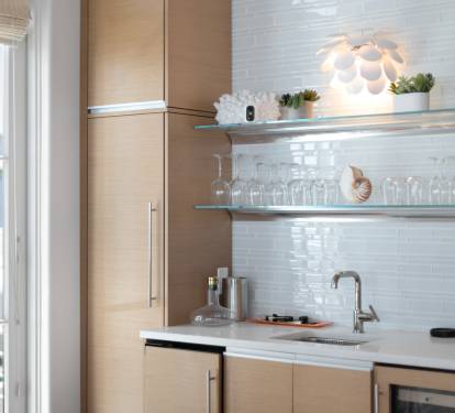 Your stylish kitchenette features modern appliances and elegant glass shelving, perfect for preparing meals with views of swaying palms.