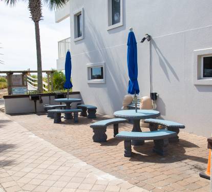 Relax on your private patio with comfortable seating and shade umbrellas, just steps from tropical palms and beach access.