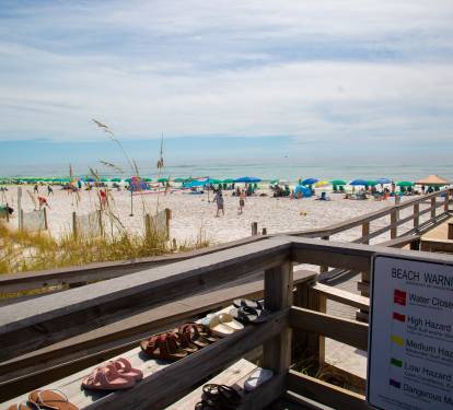 Beautiful white sand beach with colorful umbrellas and easy boardwalk access to pristine Gulf waters.