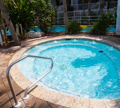 Soak in your private hot tub oasis, surrounded by lush tropical greenery and sparkling blue waters beckoning relaxation.