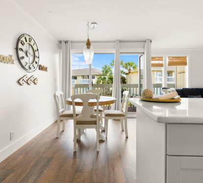 Your bright, open living space flows seamlessly from kitchen to dining, with palm trees swaying beyond your private balcony doors.