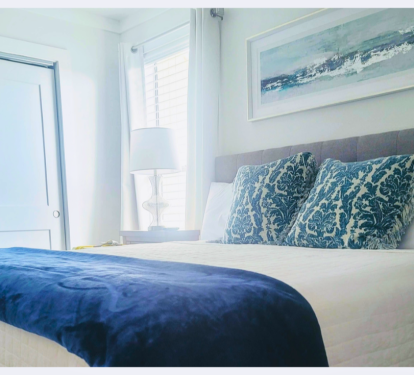 Drift off to sleep surrounded by soothing coastal blues and crisp white linens, where ocean-inspired artwork sets the perfect serene mood.
