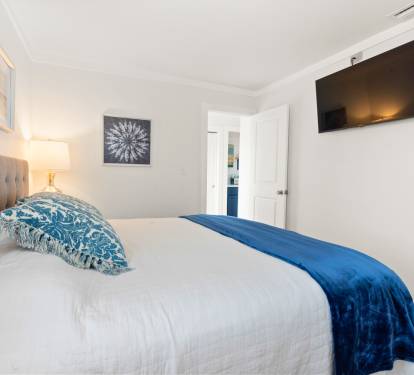 Your serene bedroom awaits with a plush tufted headboard, crisp linens, and soothing blue accents. Unwind while watching your favorite shows on the wall-mounted TV.