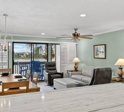 Relax in your spacious living area with comfortable seating, ceiling fan, and stunning waterfront views through sliding glass doors leading to your private balcony.