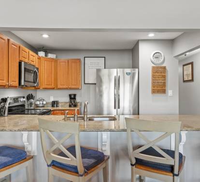 Fully equipped kitchen with stainless appliances, granite countertops, and bar seating for casual dining and conversation.