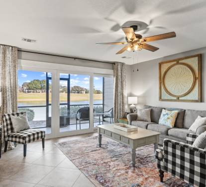 Bright coastal living area with comfortable seating, peaceful lake views, and direct patio access for relaxing mornings and sunsets.