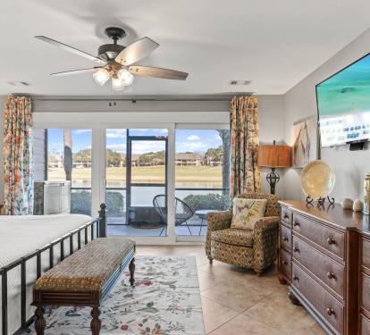Relax in the spacious primary suite with cozy seating, peaceful lake views, and direct access to the private patio.