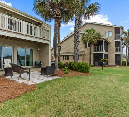 Relax on your private patio with outdoor seating while enjoying peaceful lake views through towering palm trees.