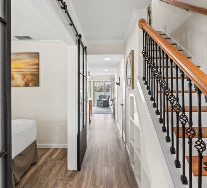 Step into your elegant hallway where warm wood floors guide you past stylish artwork toward inviting living spaces upstairs.